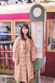 A woman standing in front of a train at a station.